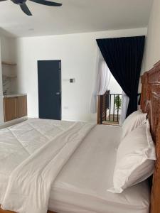a bedroom with a large white bed with a window at Timurahaus in Kajang +5 photos