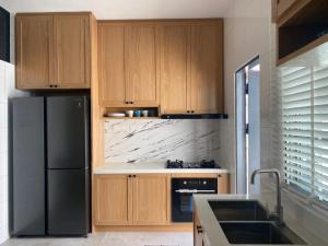 a kitchen with wooden cabinets and a black refrigerator at Timurahaus in Kajang