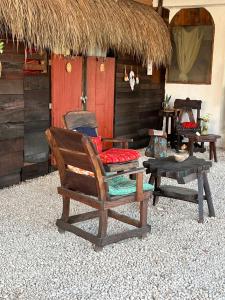 a chair and a table in front of a hut at Near Lake Hostal in Bacalar