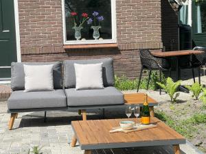 - un canapé sur la terrasse avec une table et une bouteille de vin dans l'établissement Appartement Elperhof 16A, à Schoonloo
