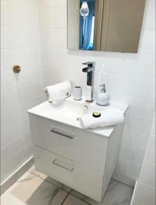 ein weißes Badezimmer mit einem Waschbecken und einem Spiegel in der Unterkunft Charmant 2 pièces à deux pas de la Croisette in Cannes