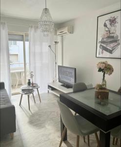 ein Wohnzimmer mit einem Tisch und einem TV in der Unterkunft Charmant 2 pièces à deux pas de la Croisette in Cannes