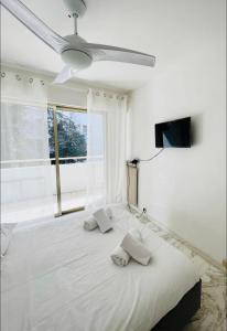 Schlafzimmer mit einem weißen Bett und einem Deckenventilator in der Unterkunft Charmant 2 pièces à deux pas de la Croisette in Cannes