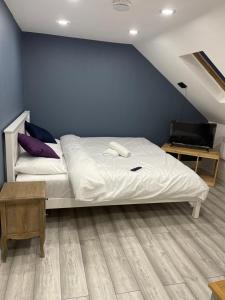 um quarto com uma cama branca e uma parede azul em EAST LONDON APARTMENTS SELF check in em Londres