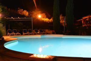 a swimming pool at night with chairs around it at Le Jardin des Gorges in Belvianes-et-Cavirac