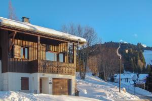 ein Haus mit Schnee auf dem Boden neben einem Gebäude in der Unterkunft Chalet de Vantaa in Les Gets