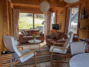 ein Wohnzimmer mit einem Sofa, Stühlen und einem TV in der Unterkunft Chalet de Vantaa in Les Gets