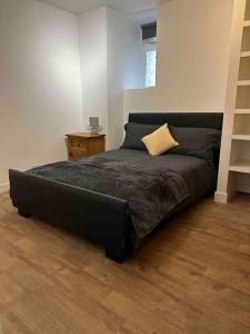 Cama negra en habitación con suelo de madera en Netherby Grange Garden Apartment with Sea Views, en Llandrillo-yn-Rhôs