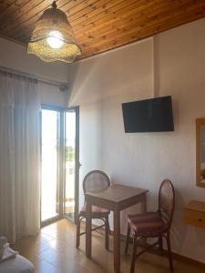 フランゴカステッロにあるArtemis Hotel-MeRaki Restaurantのテーブル、椅子2脚、テレビが備わる客室です。