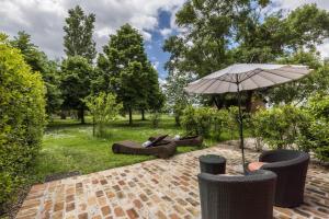 un patio con sombrilla y algunas sillas y árboles en Tenuta Ca' Zen - Cottage Casetta, en Taglio di Po