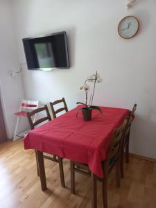 einen Esstisch mit einem roten Tischtuch und einer Uhr in der Unterkunft Tripalme Izola in Izola