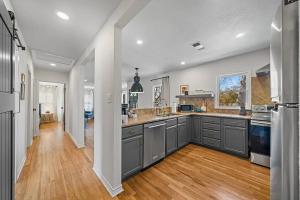 a kitchen with gray cabinets and a wooden floor at The Olive Branch - Hot Tub & Walk to Main in Fredericksburg