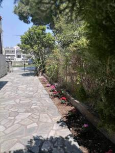 une allée en pierre avec des fleurs et des arbres et une clôture dans l'établissement Afroditi's House, à Nikiti