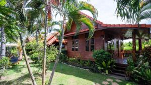 a house with palm trees in front of it at Bangsaray Village Resort in Ban Nong Chap Tao