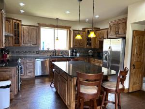 a kitchen with wooden cabinets and a kitchen island with chairs at Private Retreat on Working Horse and Cattle Ranch in Salida