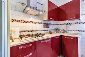 a kitchen with red cabinets and a sink at Casa Marina in Rosolina