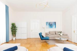 a white living room with a couch and a blue chair at Spacious and Near Metro, Perfect for Groups of 14 in Vienna