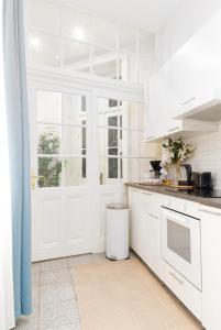cocina blanca con armarios blancos y ventana en Spacious and Near Metro, Perfect for Groups of 14 en Viena