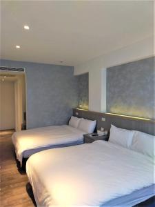 2 bedden in een hotelkamer met witte lakens bij 棉花雲文旅民宿B&B in Ch'ao-yang