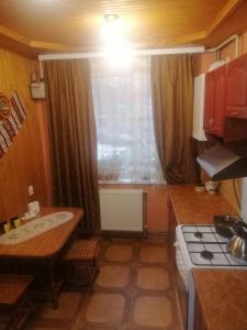 Il comprend une petite cuisine avec une cuisinière et une fenêtre. dans l'établissement Садиба Криниченька, à Yaremtche
