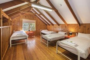 three beds in a room with wooden walls and wooden floors at Riverscape Cottages in Augusta