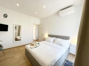 un dormitorio con una cama blanca con un perro sentado en ella en V12 Apartments Puglia, en Modugno
