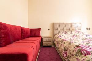 1 dormitorio con 1 cama y 1 sofá rojo en App GH7, en Agadir