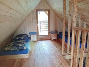 ein Zimmer mit Bett und Fenster im Dachgeschoss in der Unterkunft Drewniany Domek Małgorzatka in Żuków