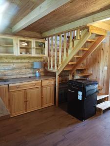 una cocina con armarios de madera y una escalera en una cabaña en Drewniany Domek Małgorzatka, 