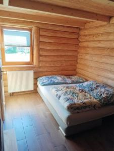 1 dormitorio con 1 cama en una cabaña de madera en Drewniany Domek Małgorzatka, 