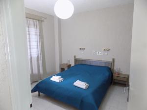 a bedroom with a blue bed with two towels on it at Afrodite Spacious Apartments! in Ayia Evfimia