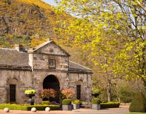 an old stone building in front of a mountain at Prestonfield House in Edinburgh