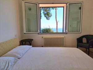 a bedroom with a bed and a large window at Appartamento in Villa Mimosa in Cervo