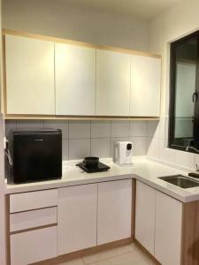 a kitchen with white cabinets and a sink and a microwave at MUJI Home KL in Kuala Lumpur