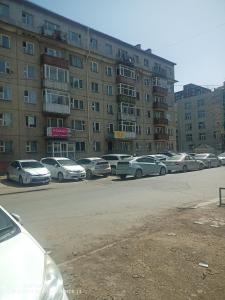 una fila de autos estacionados frente a un edificio en tsogoo's geust house, en Ulán Bator