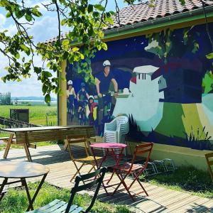 a mural on the side of a house with chairs and a table at La Maison Berry, hébergement avec petit-déjeuner in Puch-dʼAgenais