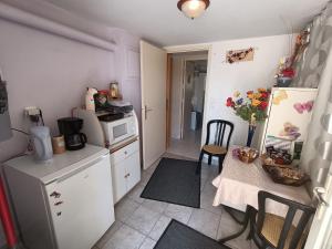 a small kitchen with a table and a refrigerator at chez jocelyne la bonnaventure in Mazangé