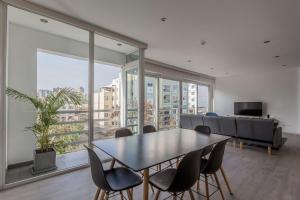 a dining room with a table and chairs and a couch at Monochromatic 2BR in Miraflores in Lima