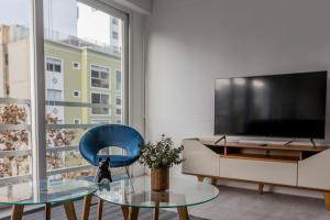 uma sala de estar com uma televisão, uma cadeira azul e uma mesa em Monochromatic 2BR in Miraflores em Lima