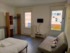 een slaapkamer met een bed, een bank en 2 ramen bij Venise - Maison avec extérieur à Reims in Reims