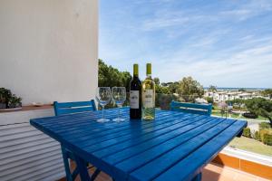 un tavolo blu con due bottiglie e due bicchieri di vino di BmyGuest - Quinta do Lago Terrace Apartment I a Quinta do Lago