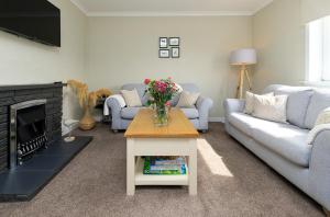 a living room with a couch and a table with flowers at Coleil Cottage in Garrabost