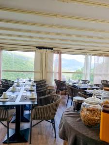 un comedor con mesas y sillas y una gran ventana en Hôtel Villa Les Orangers, en Olmeto