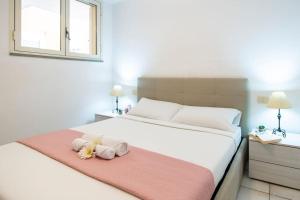 ein Schlafzimmer mit einem Bett mit zwei ausgestopften Tieren auf einer rosa Decke in der Unterkunft [Torregrande]APT.1-Con terrazzo a pochi metri dal mare - Free Wi-Fi in Torre Grande
