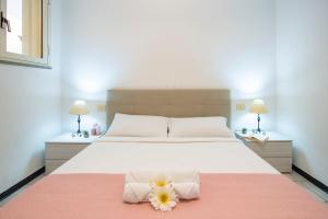 ein Schlafzimmer mit einem Bett mit Handtüchern und zwei Blumen darauf in der Unterkunft [Torregrande]APT.1-Con terrazzo a pochi metri dal mare - Free Wi-Fi in Torre Grande