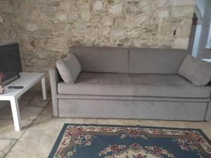 a couch in a living room with a stone wall at Porto di Mare Apartment near the sea in Molfetta
