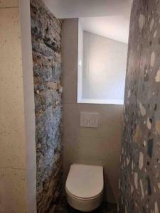 a bathroom with a white toilet and a stone wall at Appartement au cœur de la ville in Corte
