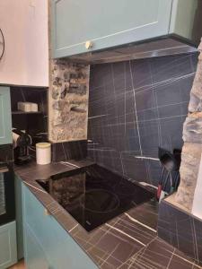 uma cozinha com bancada preta e azulejos pretos em Appartement au cœur de la ville em Corte