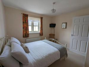 a bedroom with a white bed and a window at Cosy coach house in historical Tetbury in Tetbury