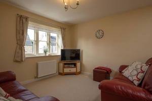 a living room with a couch and a flat screen tv at Cosy coach house in historical Tetbury in Tetbury